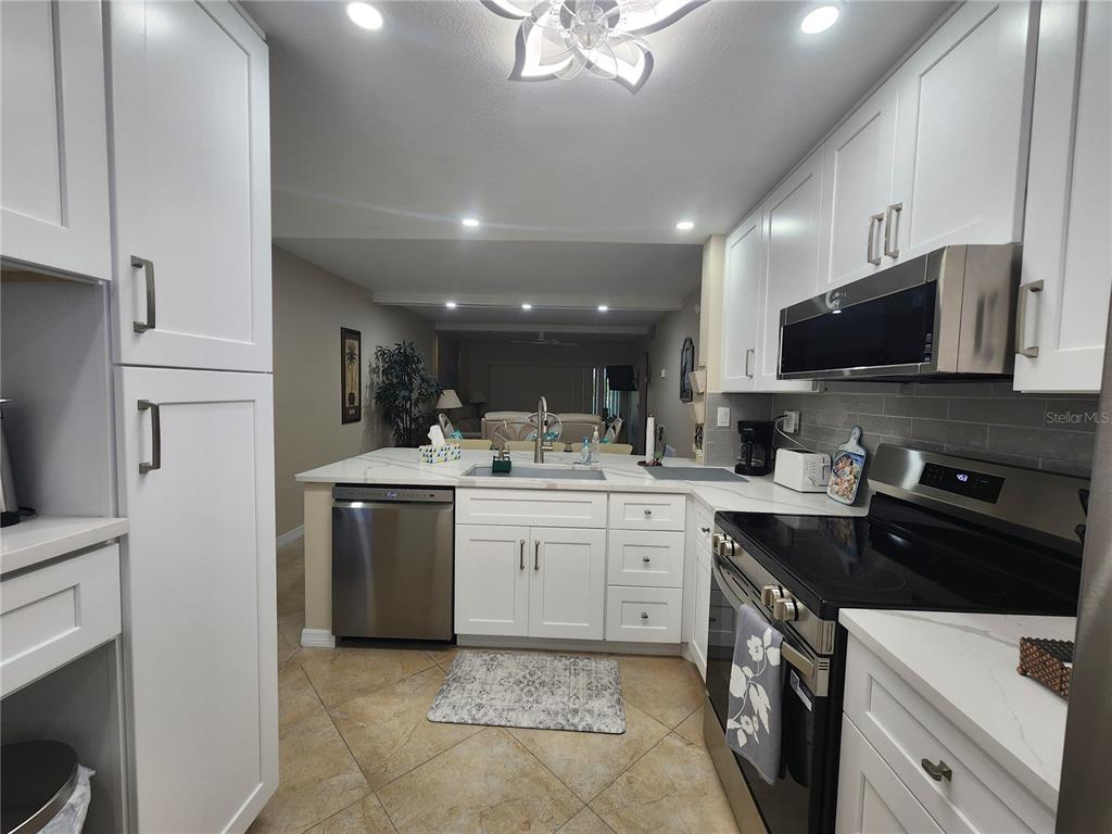 A kitchen features white cabinets, stainless steel appliances, and a peninsula with a sink — 6361 BAHIA DEL MAR BOULEVARD UNIT 104, ST PETERSBURG, FL