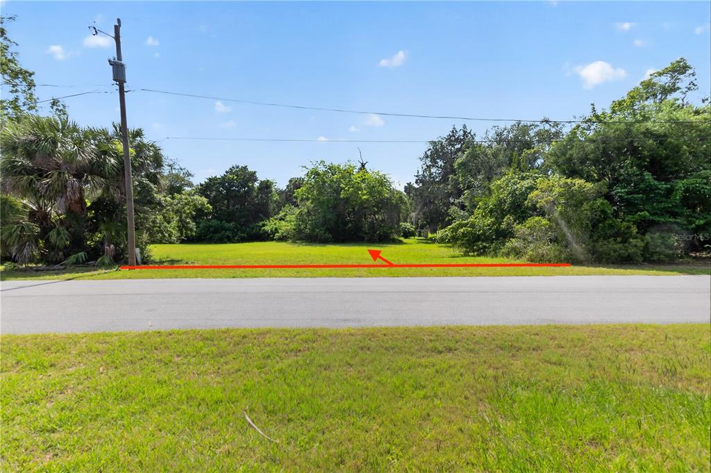 A vacant, grassy lot sits beside a paved road under a blue sky — 4540 S SAWGRASS CIRCLE, HOMOSASSA, FL