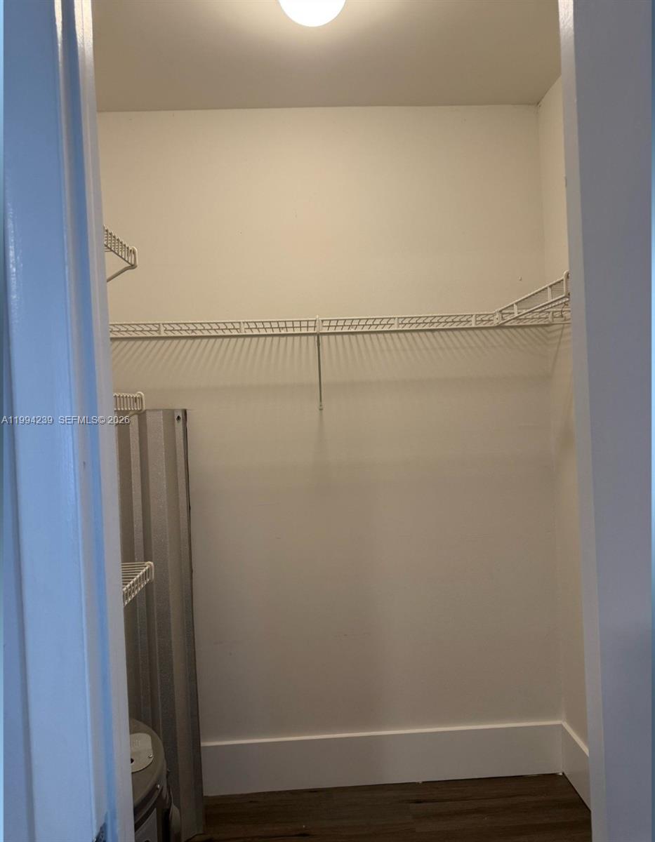 A small walk-in closet features white walls, wood-look flooring, and a wire shelving unit — 1824 Monroe St # 14, Hollywood FL 33020, HOLLYWOOD, FL
