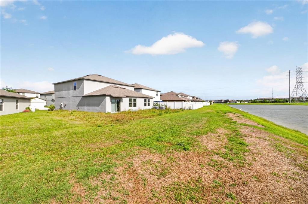 A view of the rear exterior of a suburban house overlooking a retention pond — 4712 WILD SENNA BOULEVARD, TAMPA, FL