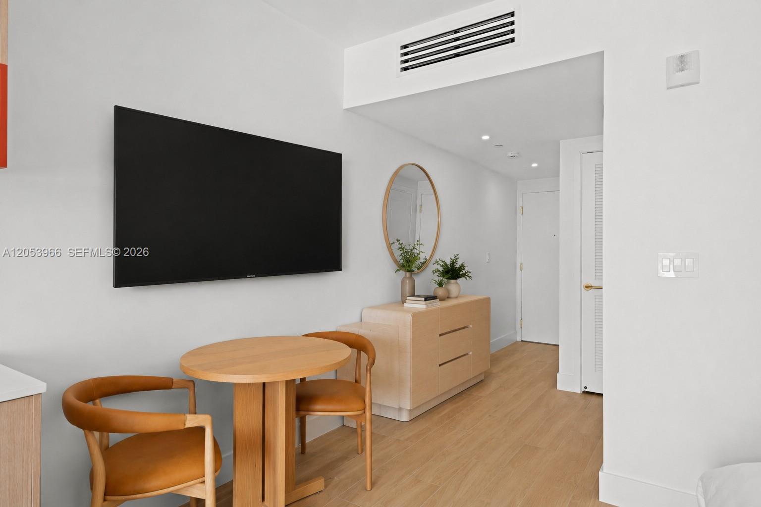 A room features a dining table with two chairs, a wall-mounted television, and a dresser — 90 NE 32nd St # 825, Miami FL 33127, MIAMI, FL