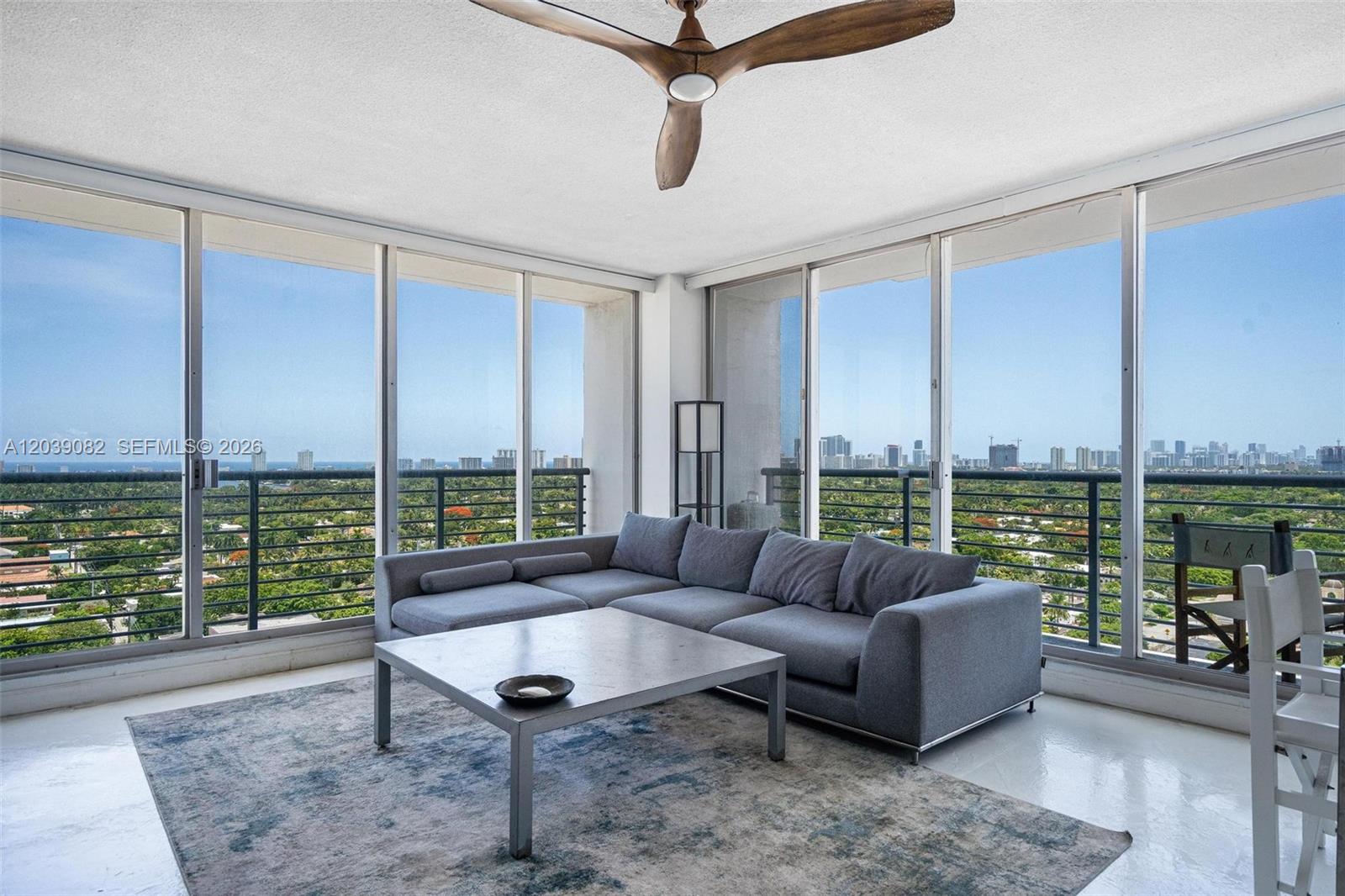 A living room features a gray sectional sofa, a coffee table, and floor-to-ceiling windows — 1720 Harrison St # 16A, Hollywood FL 33020, HOLLYWOOD, FL