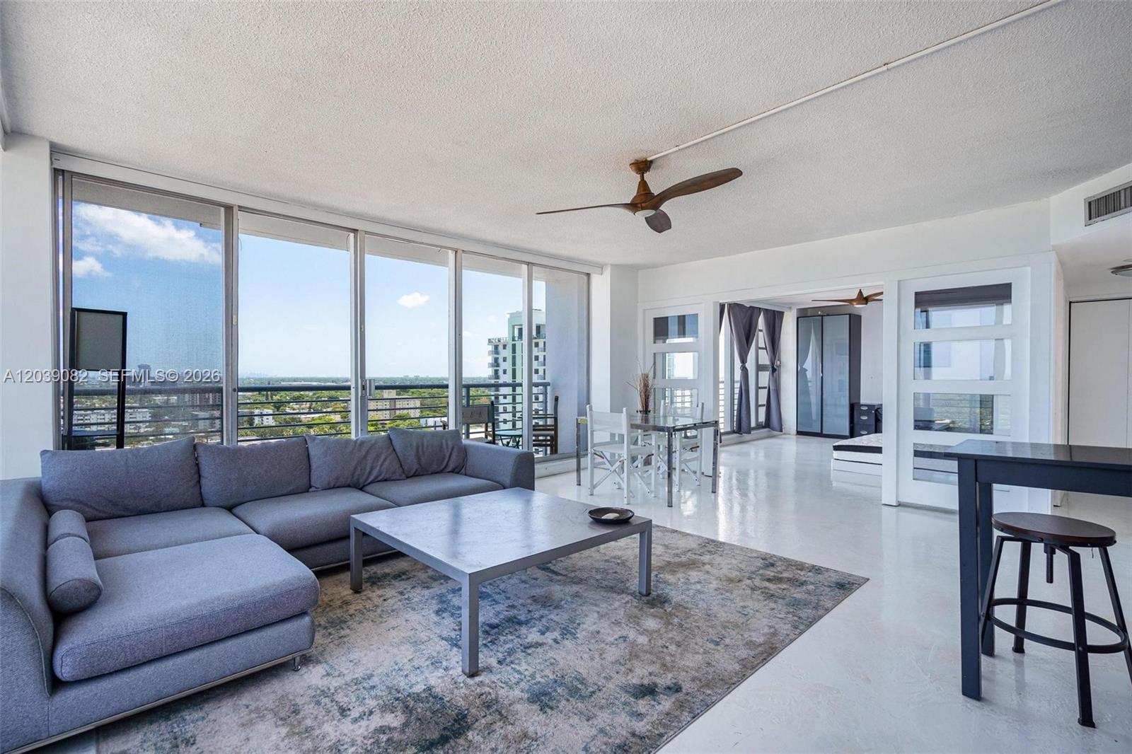 A living room with a gray sectional sofa, area rug, and floor-to-ceiling windows — 1720 Harrison St # 16A, Hollywood FL 33020, HOLLYWOOD, FL