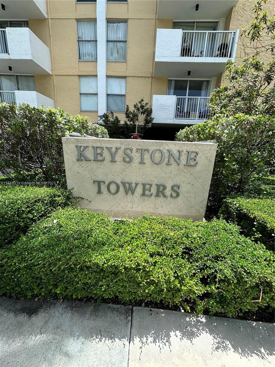The exterior of Keystone Towers features a beige building with balconies and a stone sign — 2020 NE 135th St # 807, North Miami FL 33181, NORTH MIAMI, FL