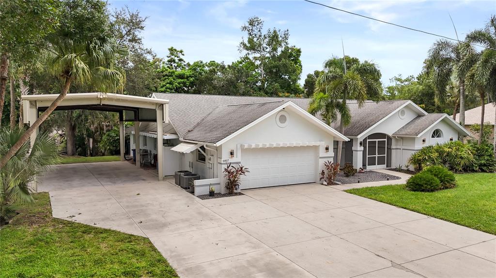 A single-story house with a white exterior, a two-car garage, and an attached metal carport — 6857 IDLEWILD STREET, FORT MYERS, FL