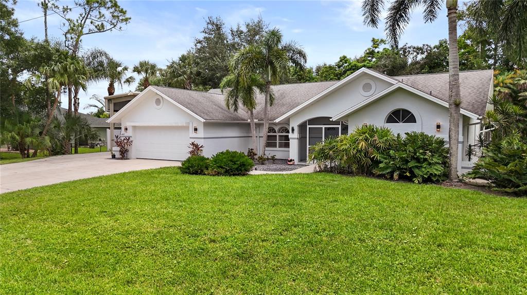 A single-story white house with a two-car garage, palm trees, and a landscaped front yard — 6857 IDLEWILD STREET, FORT MYERS, FL