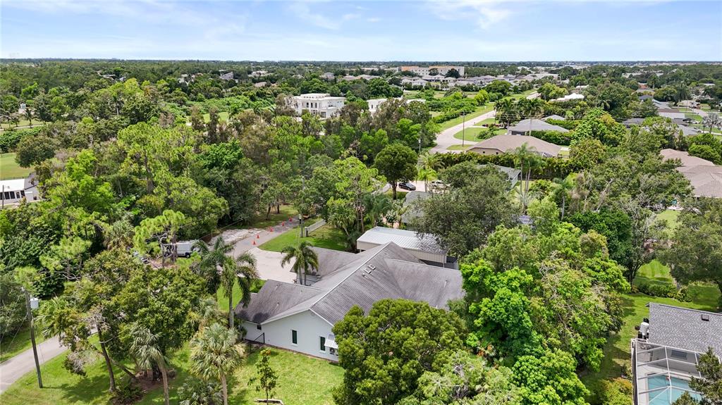 An aerial view shows a single-story house with a gray roof surrounded by dense trees — 6857 IDLEWILD STREET, FORT MYERS, FL
