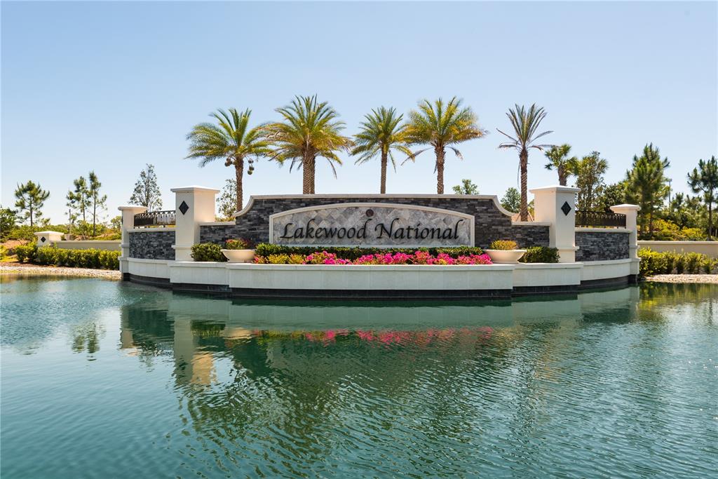 A stone monument sign for Lakewood National sits behind a pond with palm trees — 17810 GAWTHROP STREET UNIT 101, LAKEWOOD RANCH, FL
