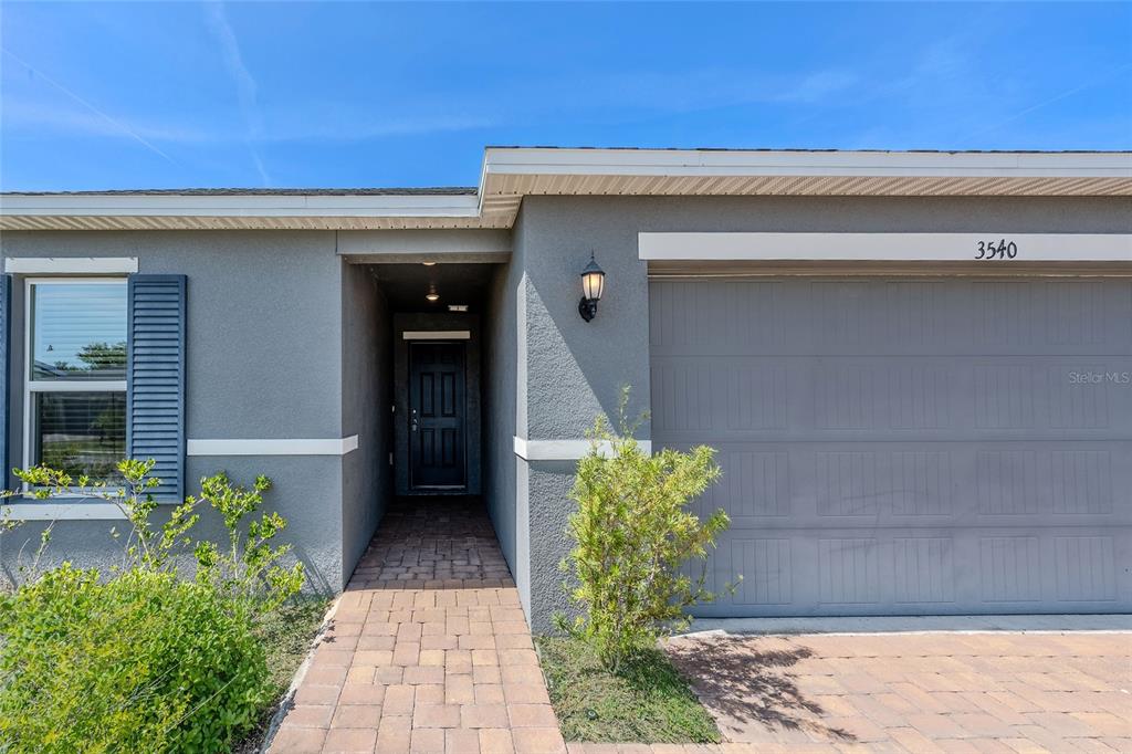 The exterior of a house features a gray stucco facade, a garage, and a walkway — 3540 74TH AVENUE CIRCLE E, SARASOTA, FL