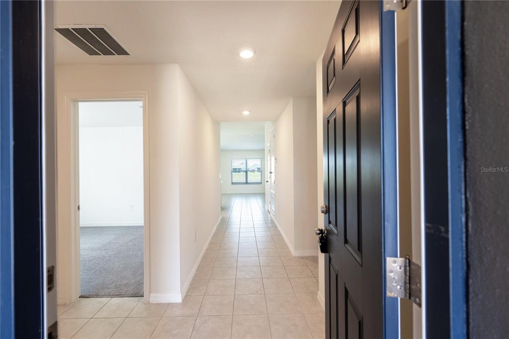 A view from an open front door into a tiled hallway with a carpeted room — 3540 74TH AVENUE CIRCLE E, SARASOTA, FL