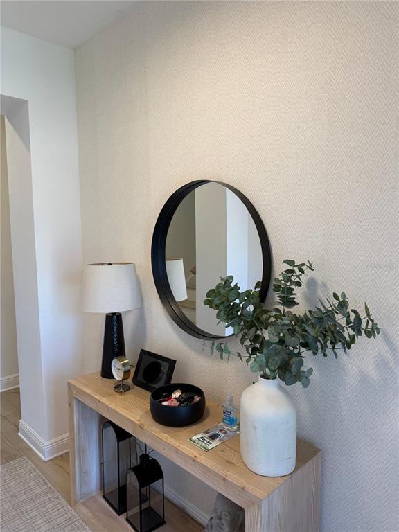 A wooden console table sits against a textured wall beneath a round black mirror — 14428 CRESTAVISTA AVENUE, CLERMONT, FL