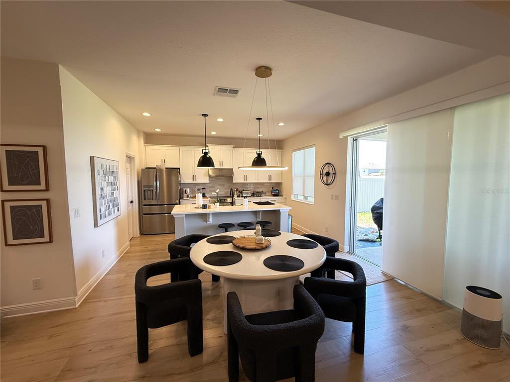 A kitchen and dining area feature white cabinetry, a central island, and a round table — 14428 CRESTAVISTA AVENUE, CLERMONT, FL
