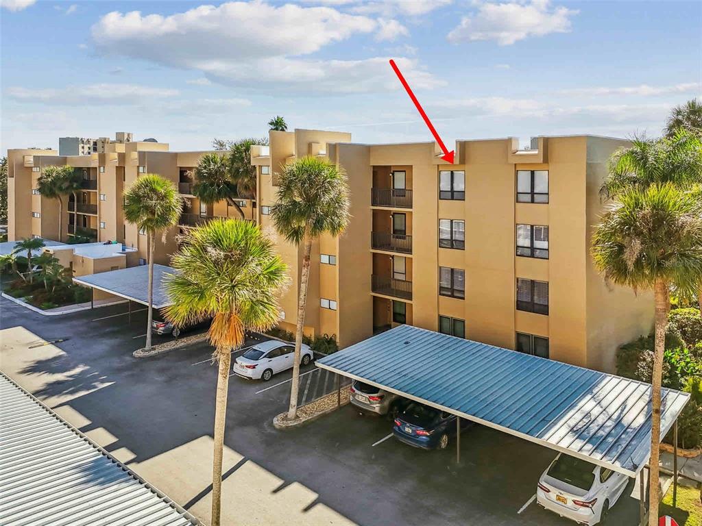 An exterior view of a multi-story apartment building with a red arrow pointing toward a window — 2615 COVE CAY DRIVE UNIT 409, CLEARWATER, FL