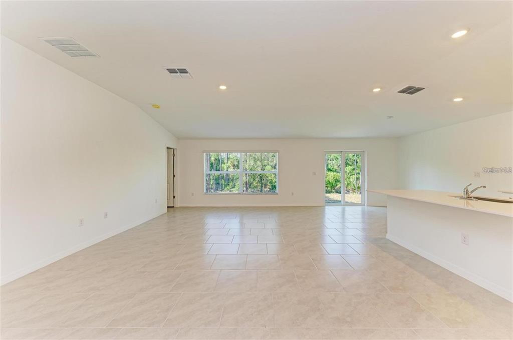 An open-concept living area features light tile flooring, white walls, and a kitchen island — 1207 SHEEHAN BOULEVARD, PORT CHARLOTTE, FL