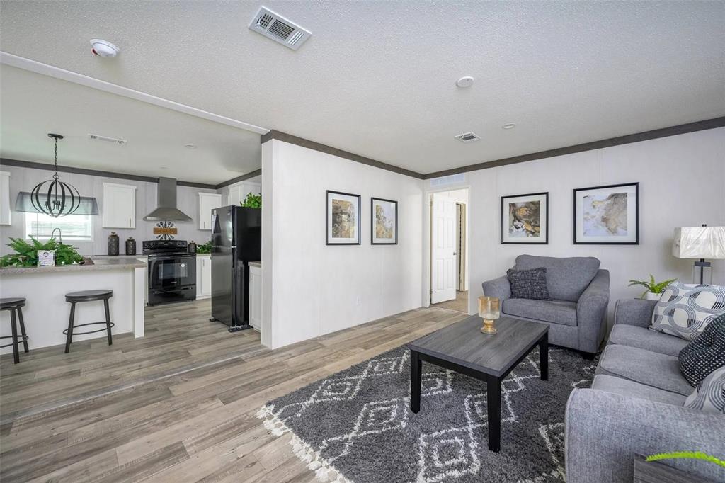 An open-concept living room and kitchen featuring gray wood-look flooring and neutral wall tones — 1041 NE COUNTY ROAD 125, LAWTEY, FL
