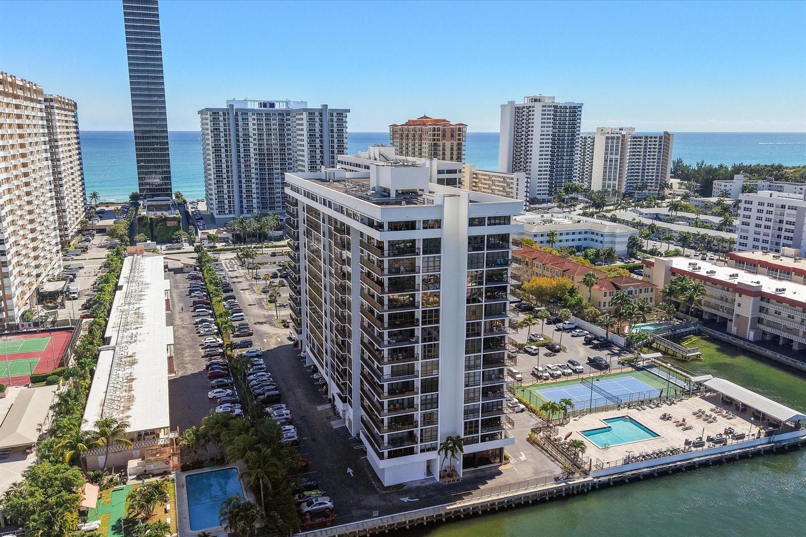 An aerial view shows a tall residential building with a pool and tennis courts nearby — 2017 S Ocean Drive, Hallandale Beach FL 33009, HALLANDALE BEACH, FL