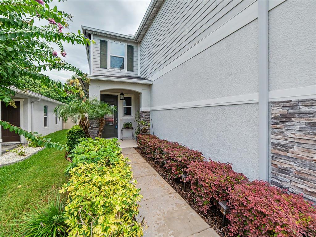 A concrete walkway leads to the front entrance of a two-story house with stone accents — 7508 SUNSHINE BRIDGE AVENUE, GIBSONTON, FL
