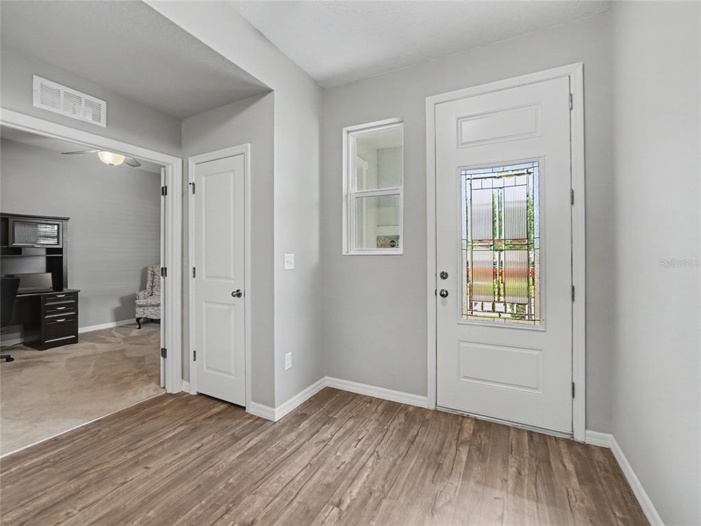 An entryway features wood-look flooring, a white front door with glass, and a nearby closet — 7508 SUNSHINE BRIDGE AVENUE, GIBSONTON, FL