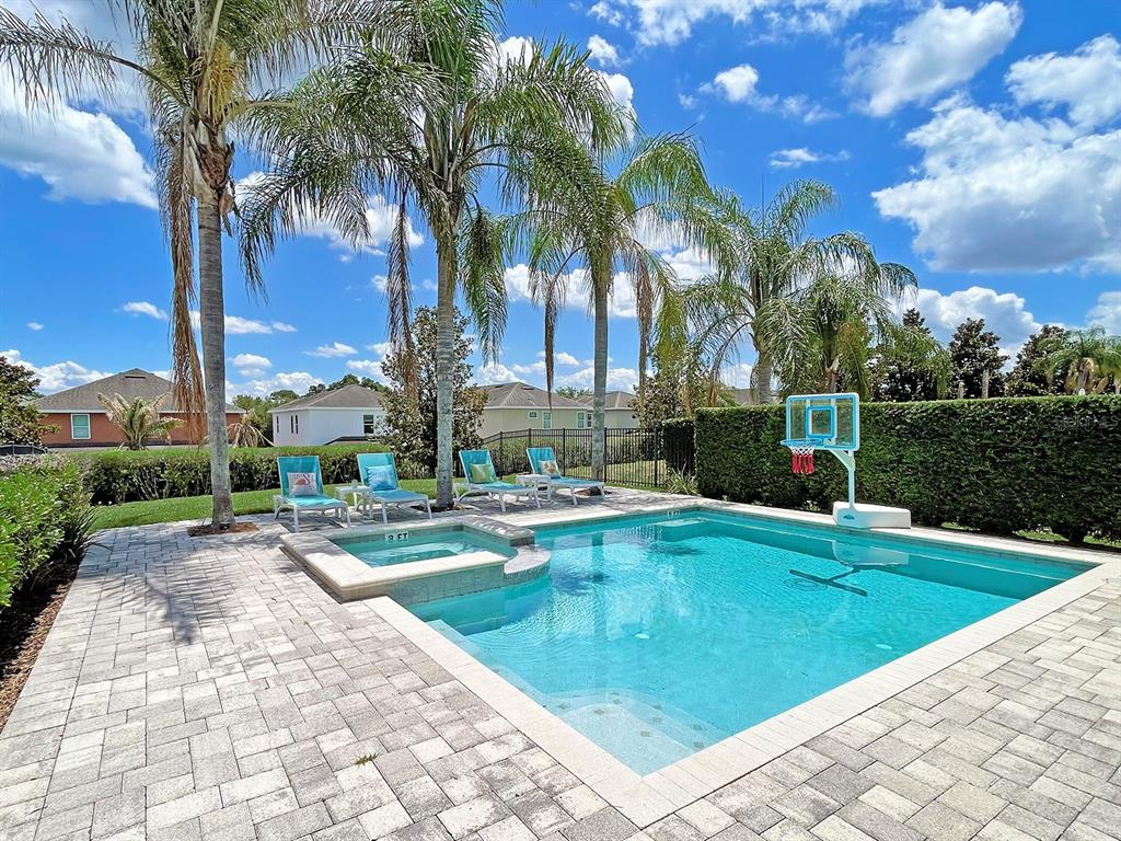 A backyard swimming pool with a spa, lounge chairs, and a basketball hoop — 7546 MARKER AVENUE, KISSIMMEE, FL