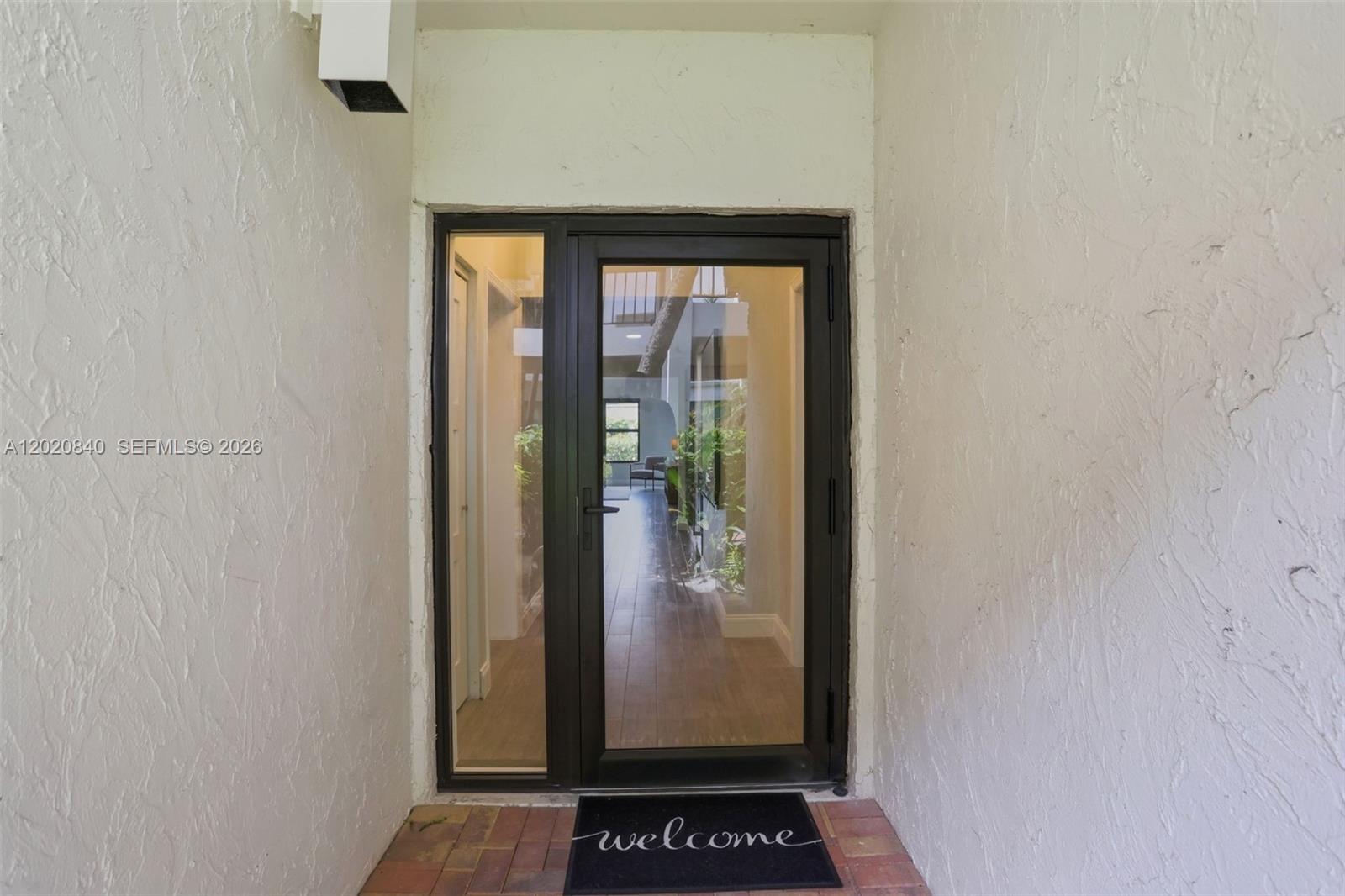 A glass-paneled front door with a side light opens into a tiled interior hallway — 830 Greensward Ct # H, Delray Beach FL 33445, DELRAY BEACH, FL