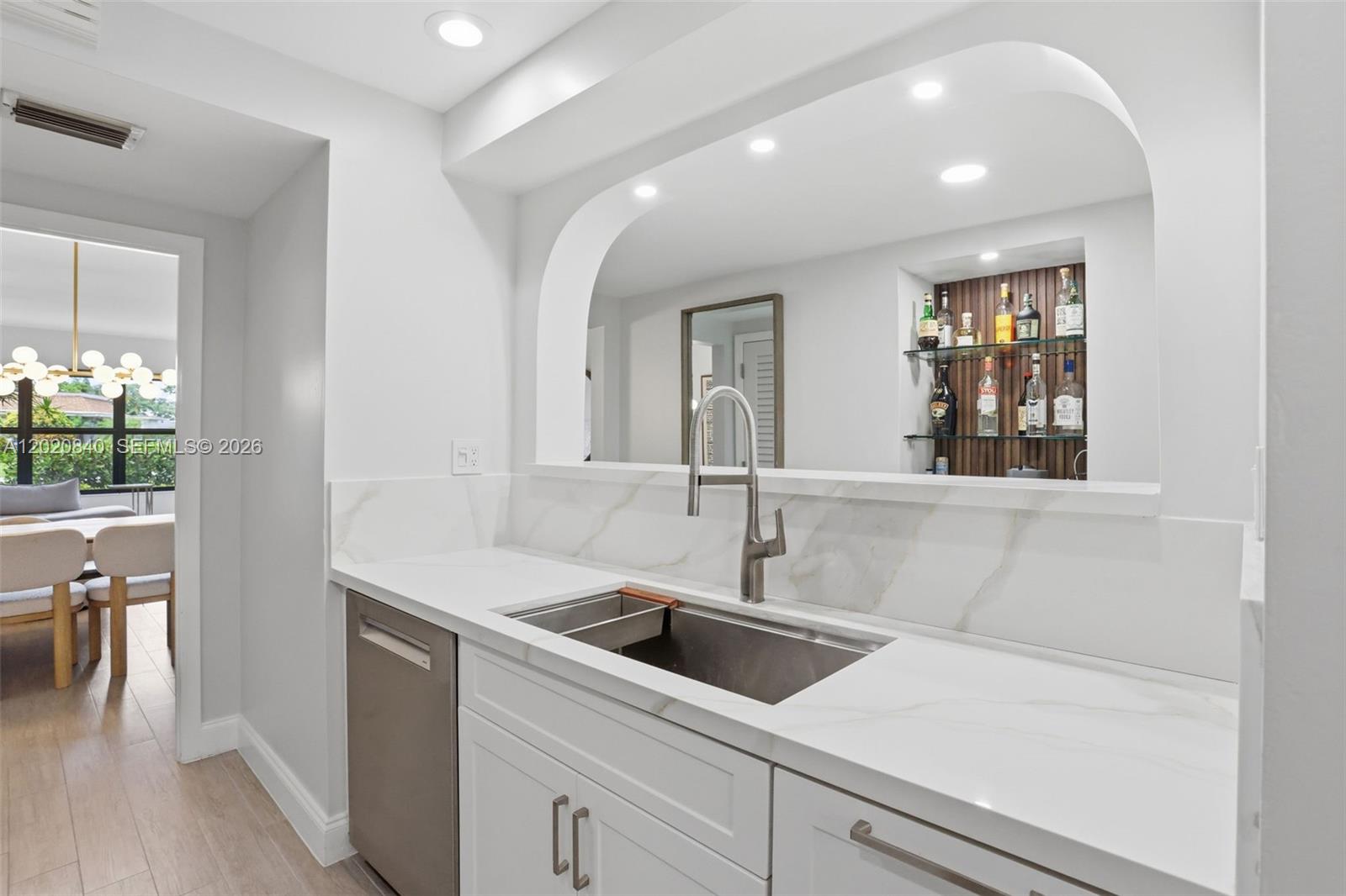A wet bar features white marble countertops, a stainless steel sink, and a mirrored alcove — 830 Greensward Ct # H, Delray Beach FL 33445, DELRAY BEACH, FL