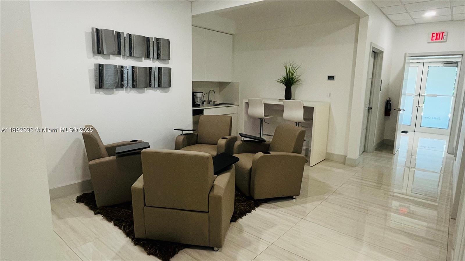 A waiting area features four tan armchairs on a rug, a kitchenette, and an exit door — 17100 Royal Palm Blvd # 1, Weston FL 33326, WESTON, FL