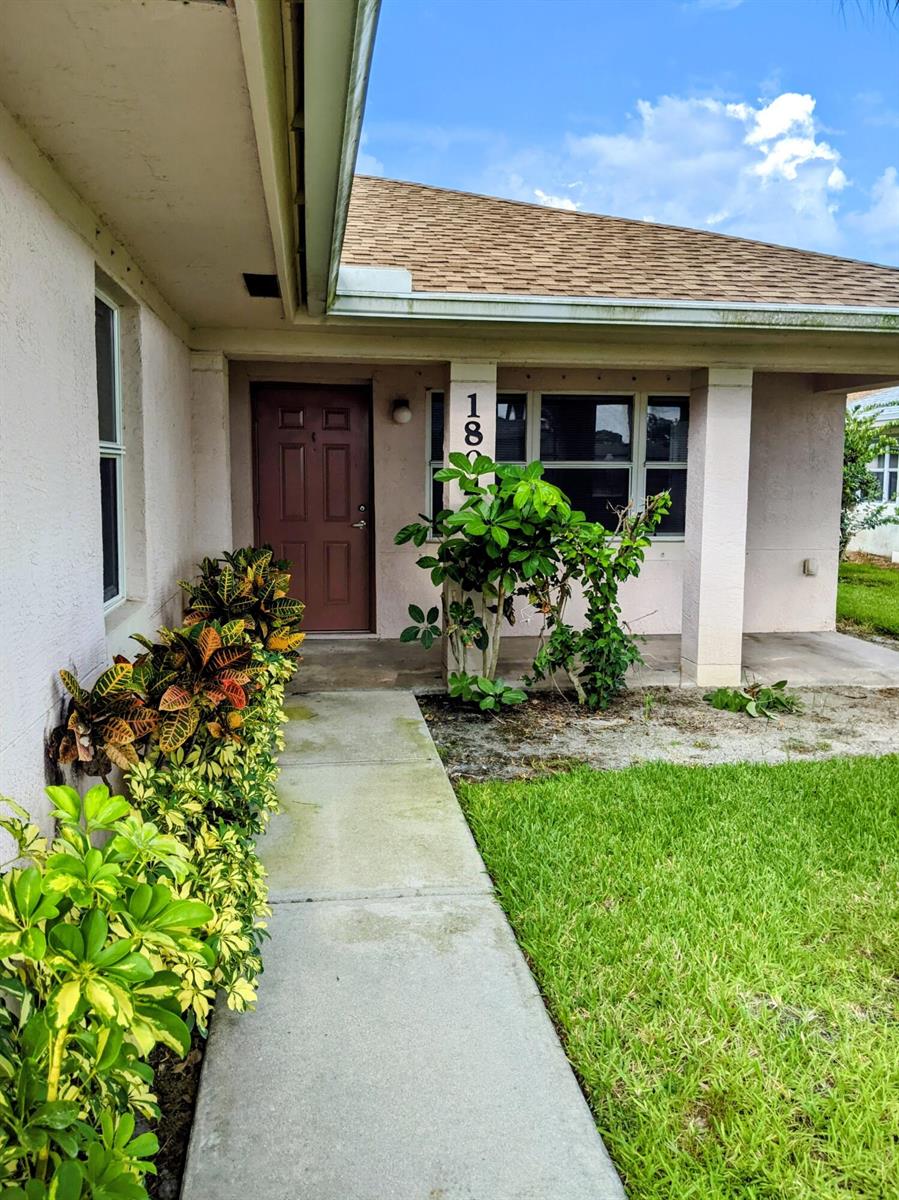 A concrete walkway leads to the front entrance of a house with a brown door — 1804 Blue Heron Lane # C, Fort Pierce FL 34982, FORT PIERCE, FL