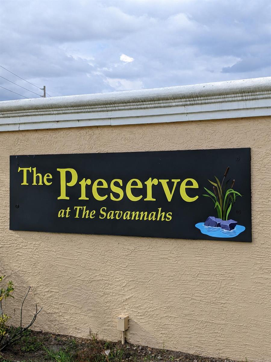 A black sign with yellow text reading The Preserve at The Savannahs on a wall — 1804 Blue Heron Lane # C, Fort Pierce FL 34982, FORT PIERCE, FL