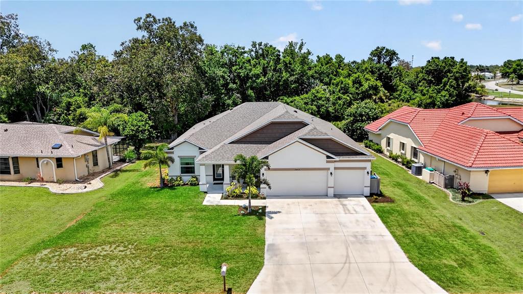 A single-story house with a beige exterior, a two-car garage, and a palm tree — 2423 MALAYA COURT, PUNTA GORDA, FL