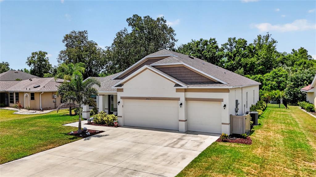 A living room features a television on a blue console, gray recliners, and tile flooring — 2423 MALAYA COURT, PUNTA GORDA, FL