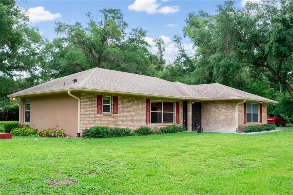 A single-story brick house with a hip roof sits on a grassy lawn — 267 N ORANGE AVENUE, LAKE HELEN, FL