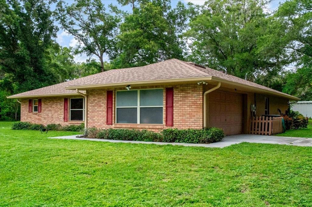 A single-story brick house with a brown shingled roof, red shutters, and an attached garage — 267 N ORANGE AVENUE, LAKE HELEN, FL