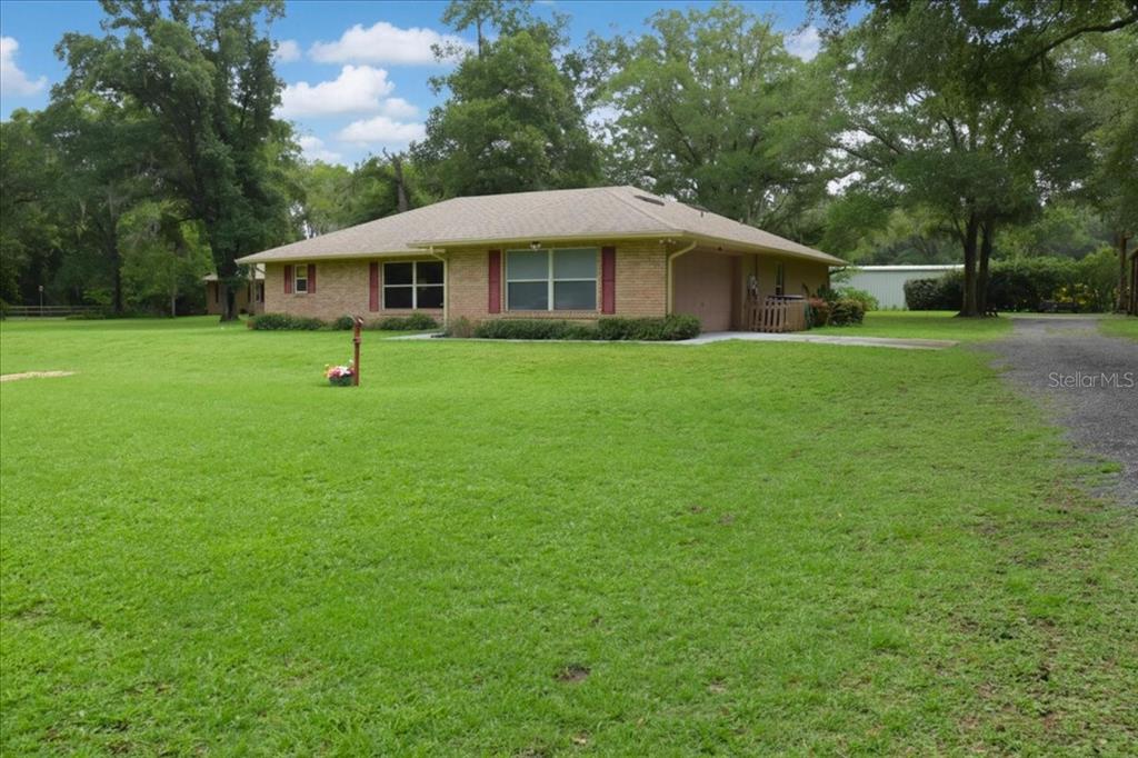 A single-story brick house with red shutters sits on a large, grassy lot — 267 N ORANGE AVENUE, LAKE HELEN, FL