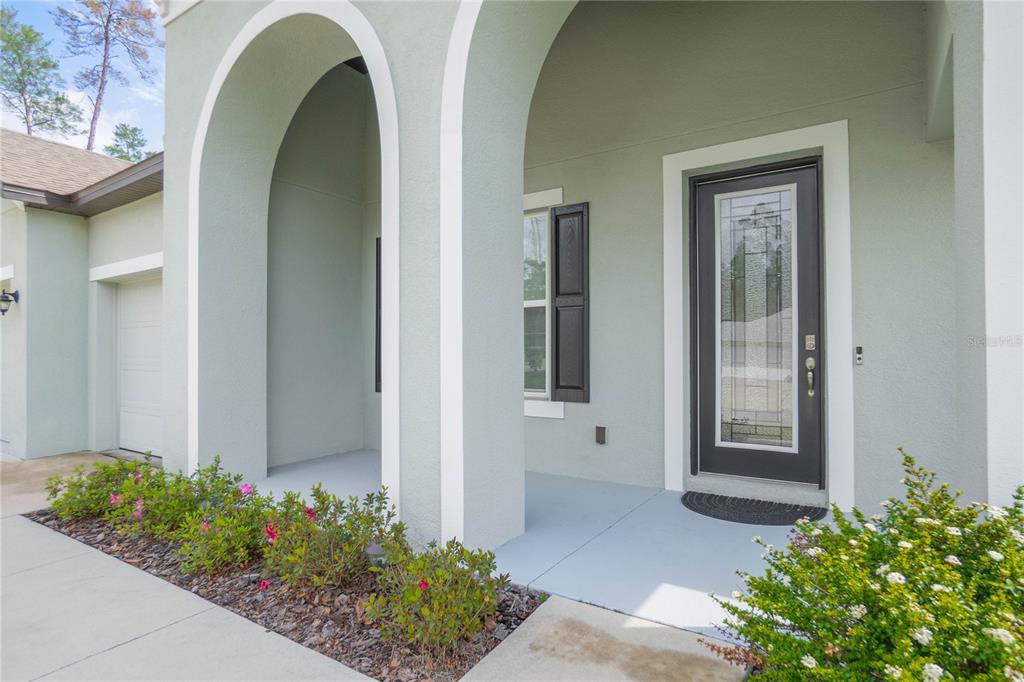 A covered entryway features a dark front door with glass inlay and arched architectural columns — 69 GRASS STREET, HOMOSASSA, FL