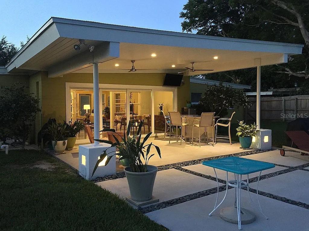 A living room features a bright yellow accent wall, terrazzo floors, and mid-century modern furniture — 1402 CUMBIE STREET, ORLANDO, FL