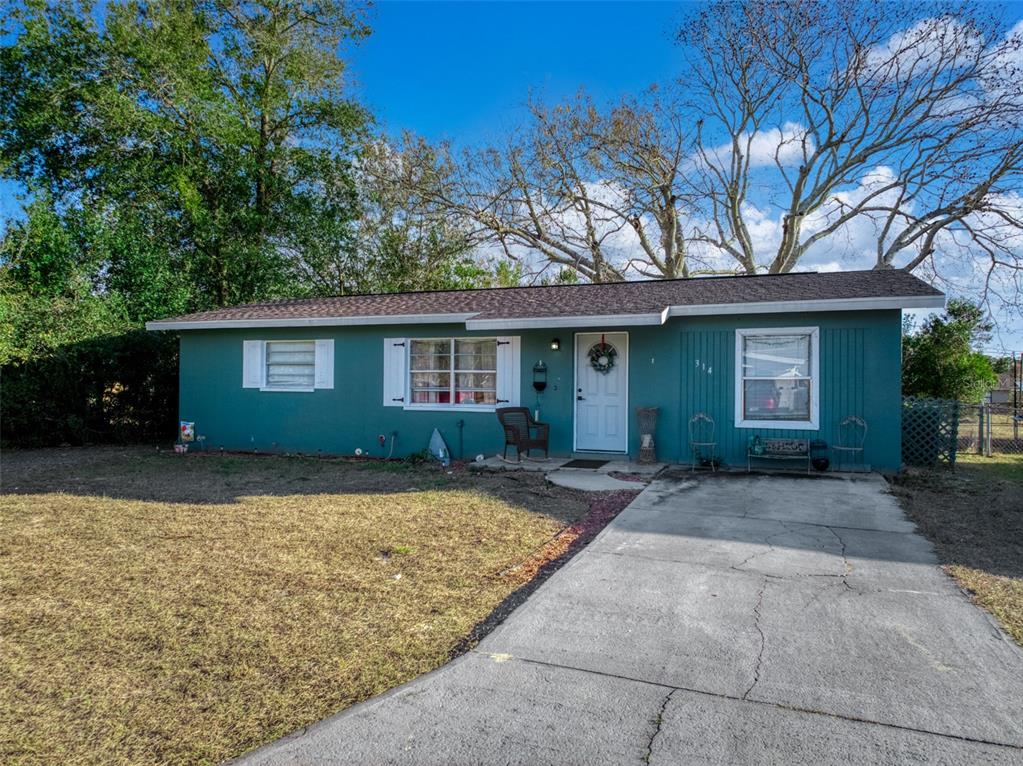 A single-story teal house with a concrete driveway and a front lawn — 314 RAIL AVENUE, SEBRING, FL