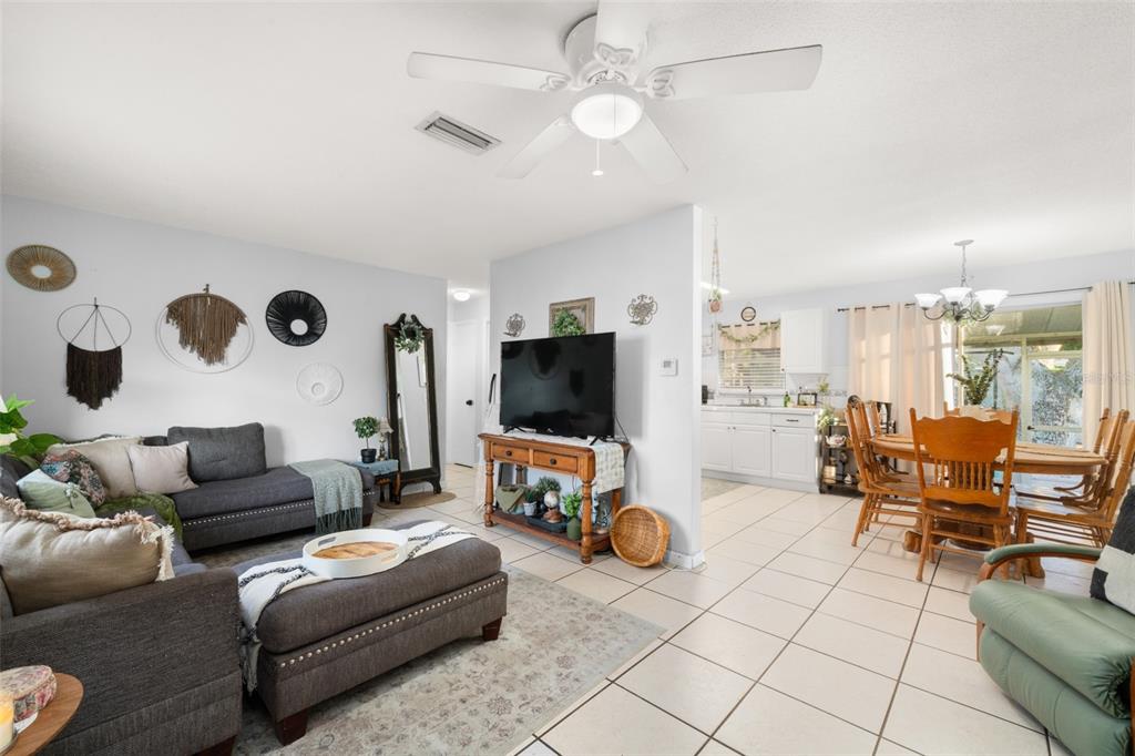A living room with a gray sectional sofa and television opens to a dining area — 314 RAIL AVENUE, SEBRING, FL