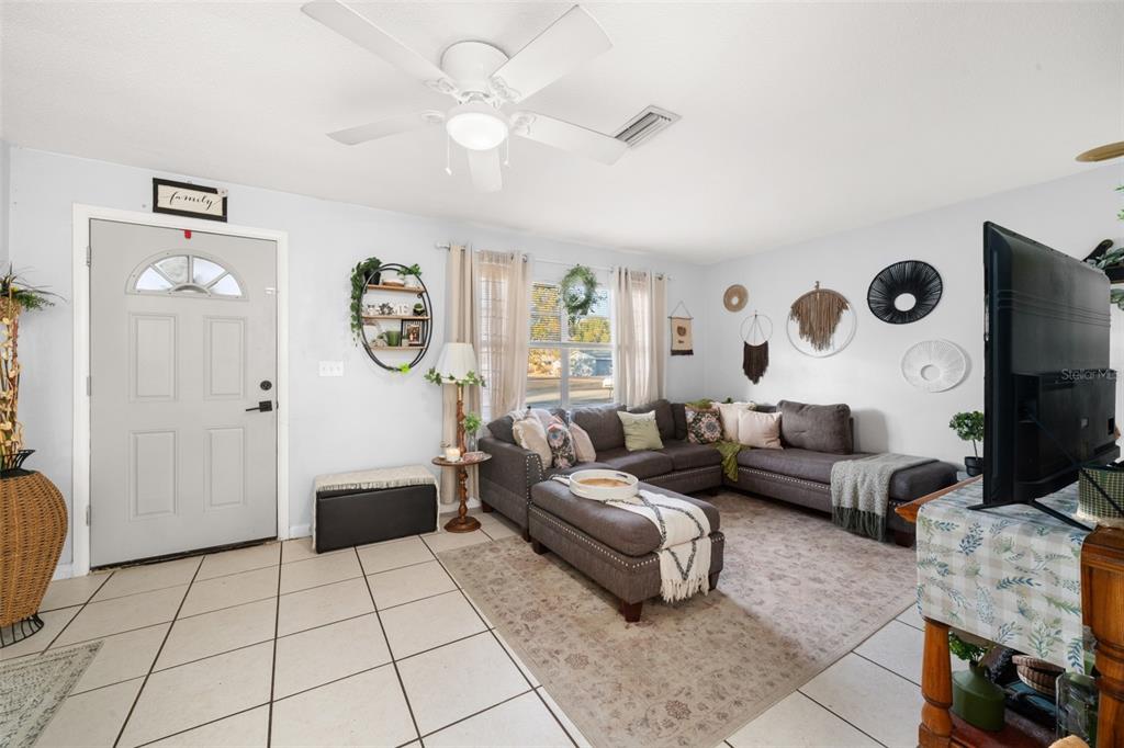 A living room features a grey sectional sofa, tile flooring, and a ceiling fan — 314 RAIL AVENUE, SEBRING, FL