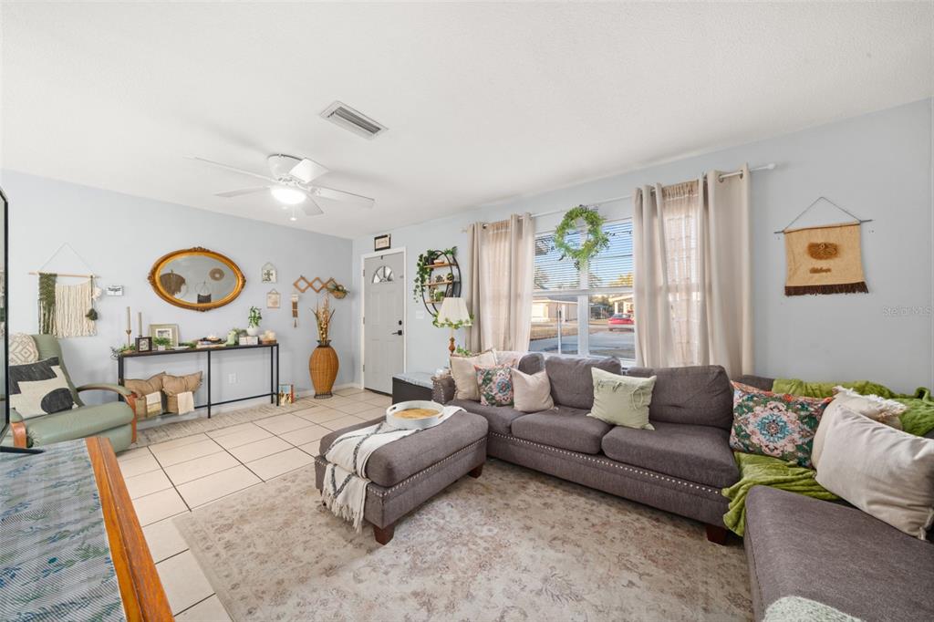 A living room features tile flooring, a gray sectional sofa, and a large window — 314 RAIL AVENUE, SEBRING, FL
