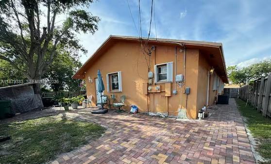 The exterior of a single-story orange house features a brick patio and a grassy yard — 2306 Liberty St # C, Hollywood FL 33020, HOLLYWOOD, FL