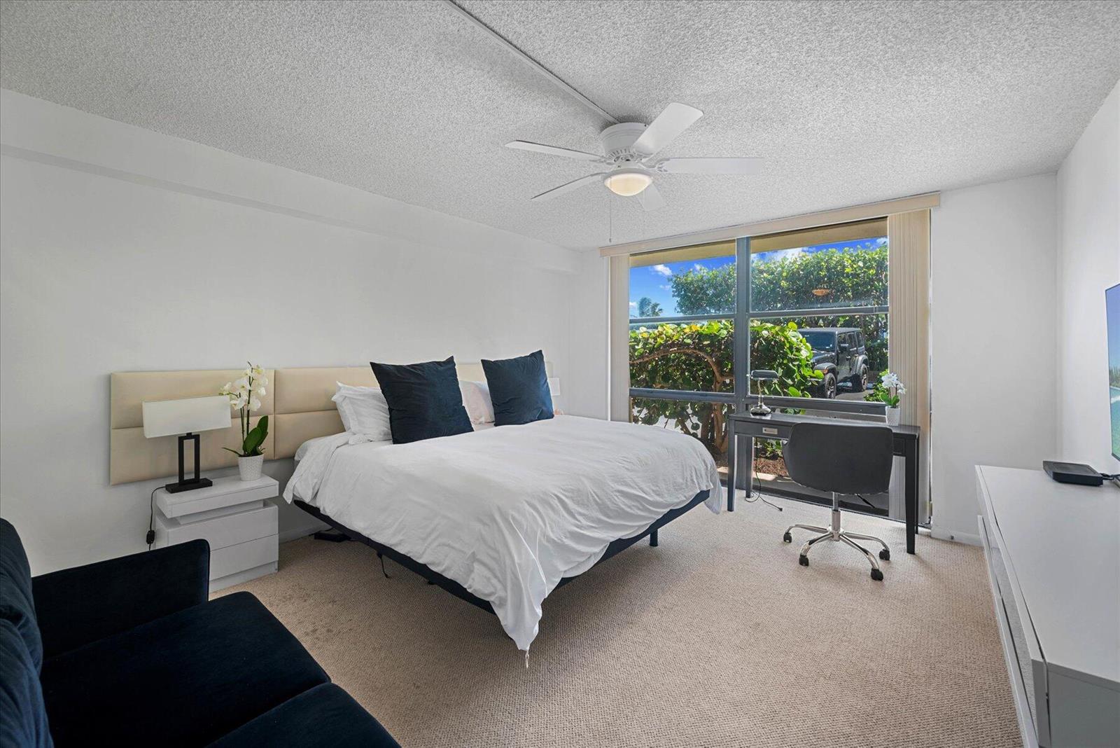 A bedroom features a bed, a desk by the window, and a ceiling fan — 3200 S Ocean Boulevard # A102, Palm Beach FL 33480, PALM BEACH, FL