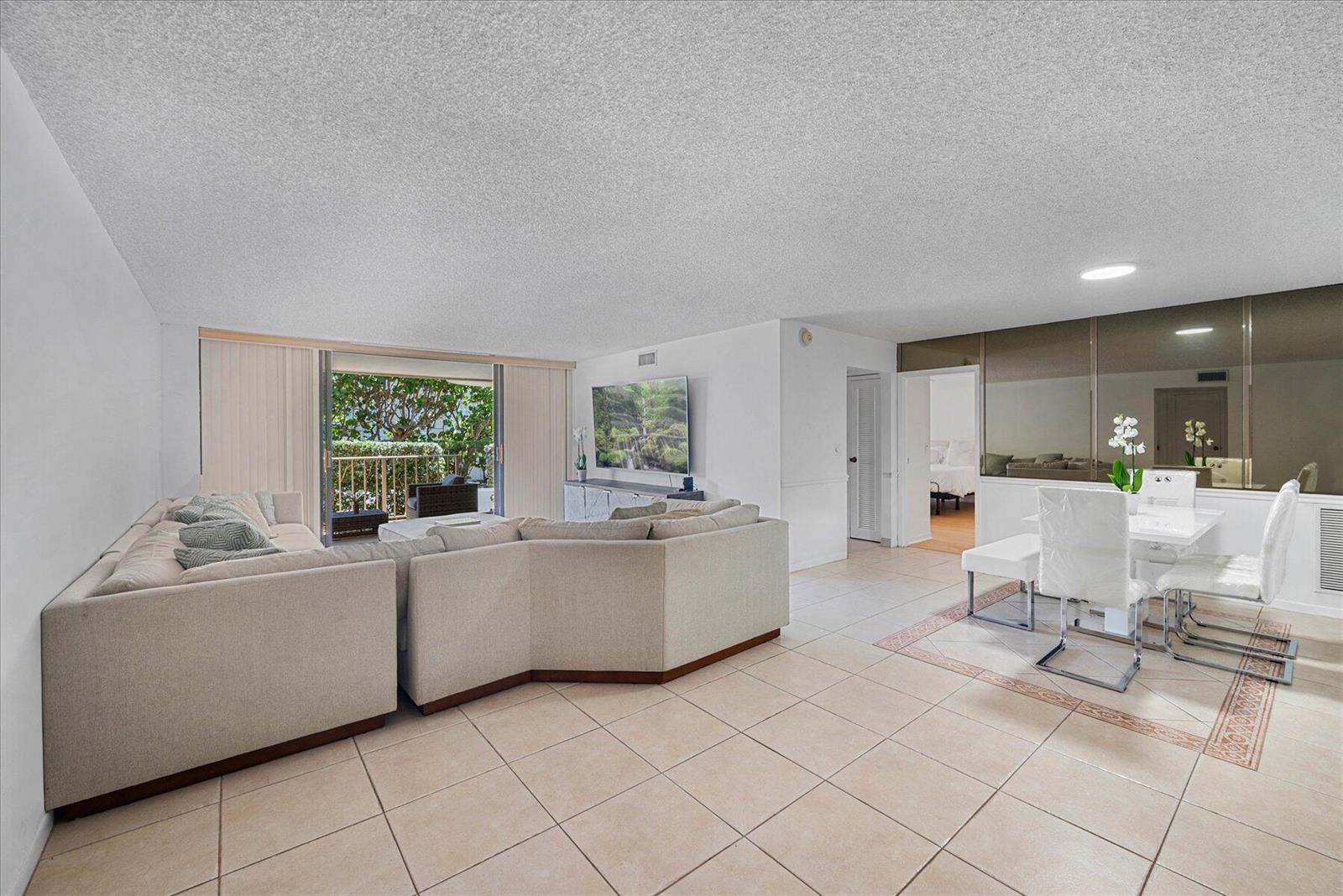 A living and dining area with tile floors, a sectional sofa, and a balcony view — 3200 S Ocean Boulevard # A102, Palm Beach FL 33480, PALM BEACH, FL