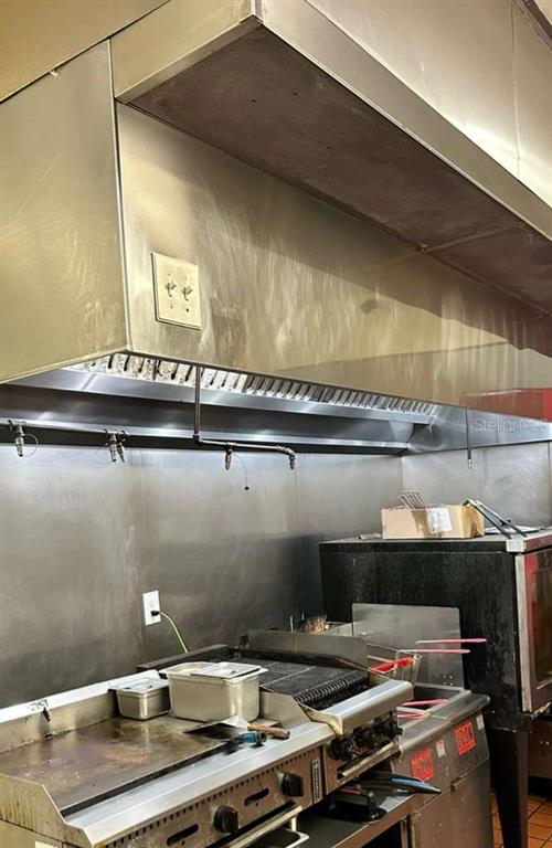 A commercial kitchen features a stainless steel vent hood above a flat-top grill and fryer — 3042 W SAND LAKE ROAD, ORLANDO, FL