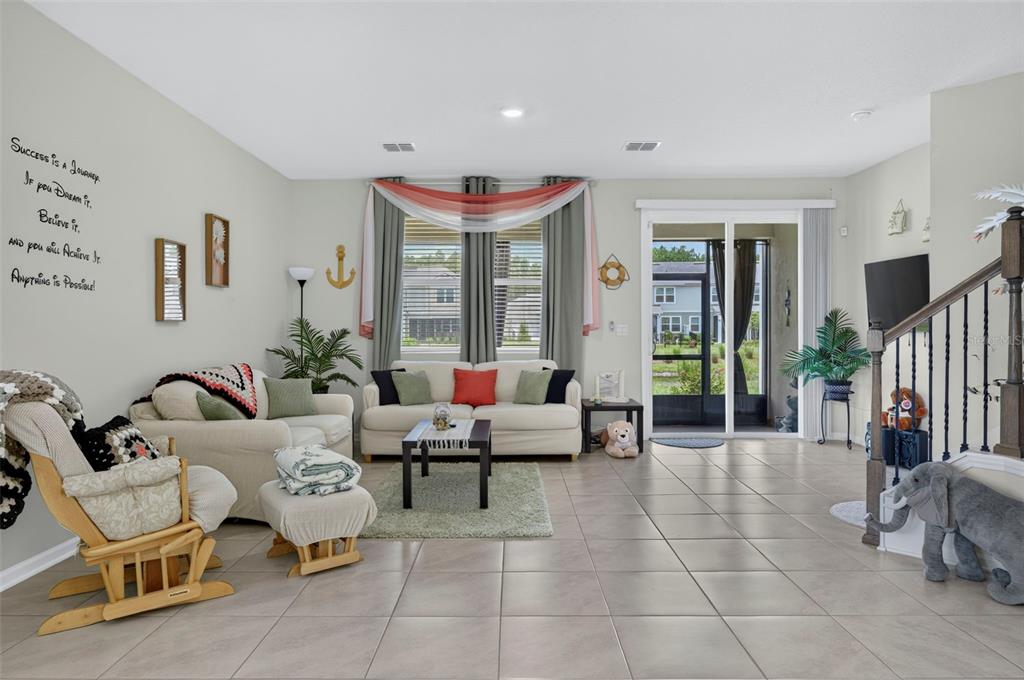 A living room features tile floors, a white sofa, a rocking chair, and sliding glass doors — 122 REDBUD ROAD, PALM COAST, FL