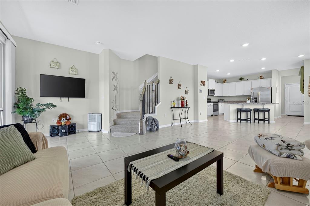 An open-concept living room with tile flooring, a staircase, and an adjacent kitchen — 122 REDBUD ROAD, PALM COAST, FL