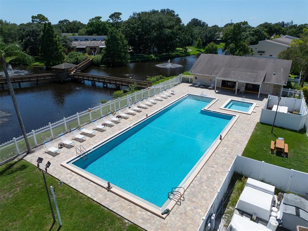 An aerial view of a rectangular swimming pool, a hot tub, and a wooden footbridge — 6494 92ND PLACE N UNIT 203, PINELLAS PARK, FL