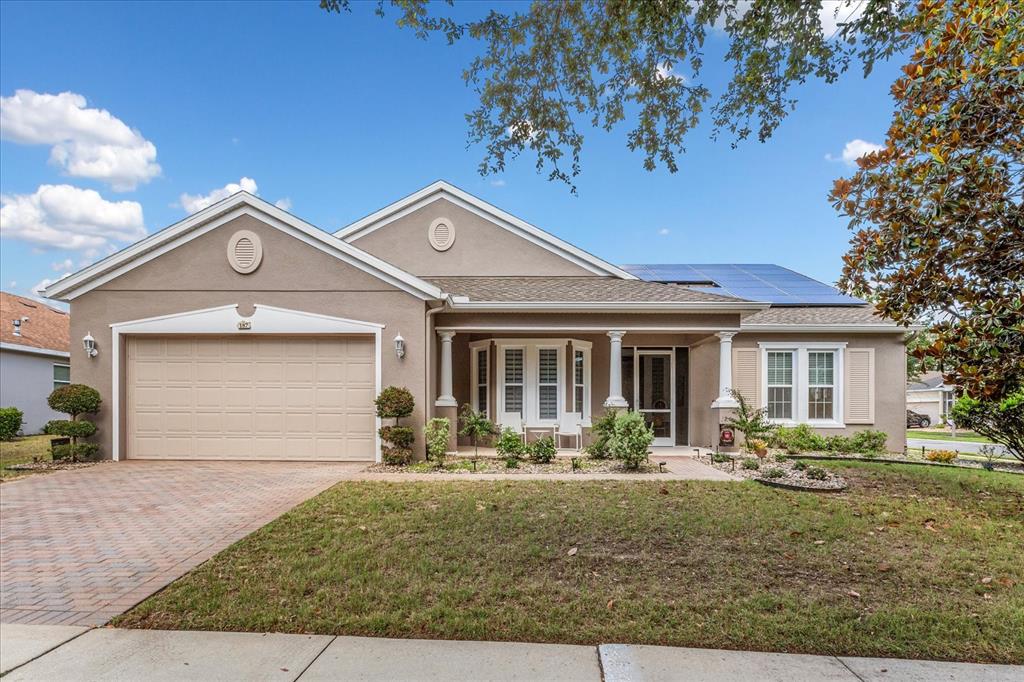 A single-story suburban house with a tan stucco exterior, a two-car garage, and solar panels — 187 BALMY COAST ROAD, GROVELAND, FL