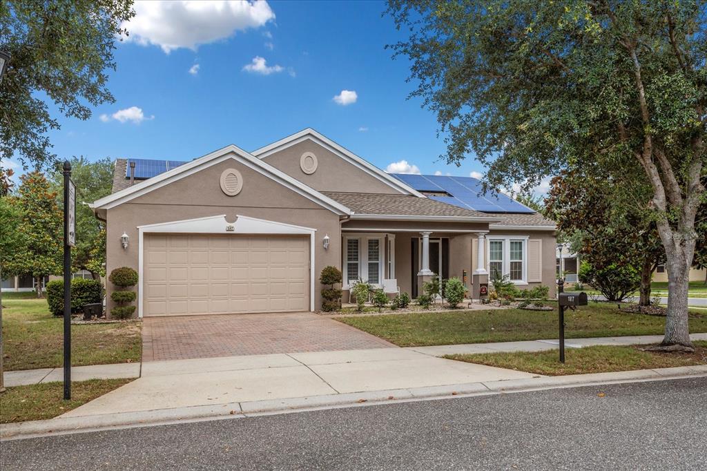 A single-story suburban house with a tan stucco exterior, a two-car garage, and solar panels — 187 BALMY COAST ROAD, GROVELAND, FL