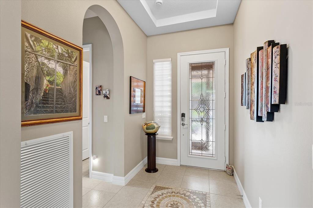 A tiled entryway features an arched doorway, a glass-paneled front door, and decorative wall art — 187 BALMY COAST ROAD, GROVELAND, FL