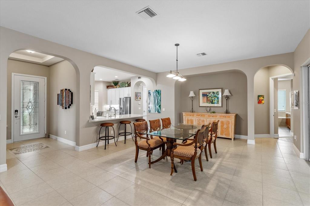 A dining room with a glass table, chairs, and a breakfast bar overlooking the kitchen — 187 BALMY COAST ROAD, GROVELAND, FL